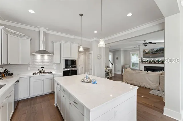 Kitchen with gas range, vent hood and white cabinetry at 5 Caspian Lane